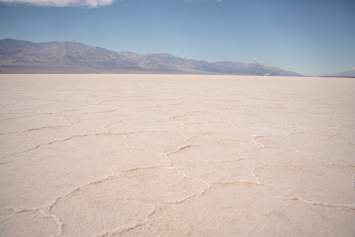 White salt polygons extending toward distant mountains beneath a blue sky at Badwater Basin.